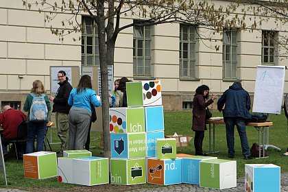 Das Wrfelpuzzle der Aktion Mensch mit dem bunten Inklusionszeichen und Fakten zur Behinderung ld zur Begegnung von Menschen mit und ohne Behinderung ein